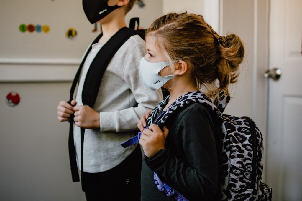A young girl stands with a Covid mask on