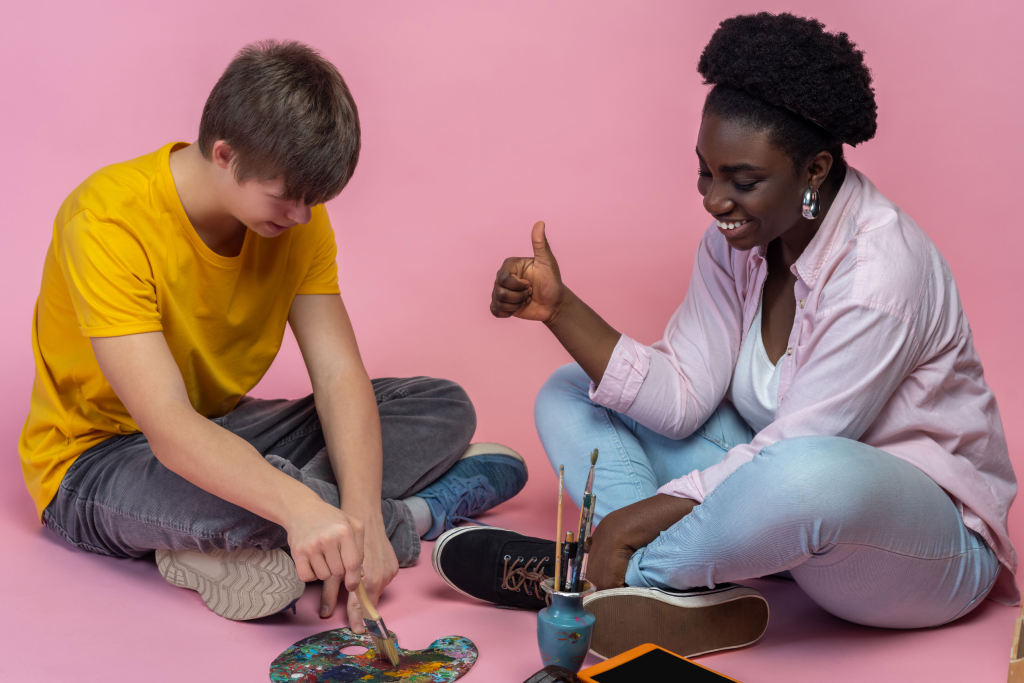 A young art therapist works with a teenage boy with downs syndrome